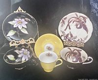 Front view of all three cup and saucer sets displayed on stands