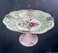 Side perspective showing pedestal form, scalloped reticulated rim and floral center