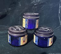 Three cobalt blue Noxzema jars stacked showing labels and lids