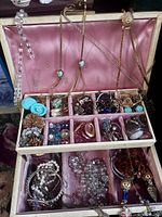 Open jewelry box showing upper tray compartments filled with assorted jewelry pieces