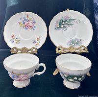 Front view of both teacups with saucers displaying floral designs