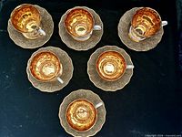 Top view of six gold-lined cups on matching saucers