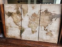 Front view of three canvas panels together forming world map