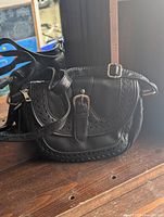 Front view showing flap with buckle, scalloped perforations, strap