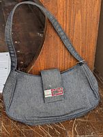 Front view showing denim body, strap, and logo flap