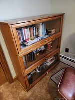 Front view of three-section barrister bookcase filled with books and collectibles