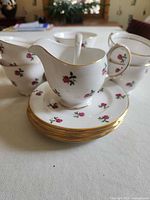 saucers stacked with creamer in foreground, teacups visible