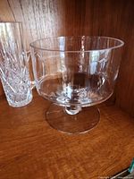 Clear glass footed trifle bowl beside cut-glass pitcher