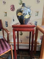 Vase on wooden stand beside chair, full view