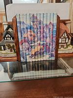 Front view of both resin cottages mounted on wood bookends with booklet between