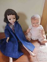 Both dolls seated on wooden surface