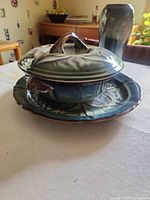 Covered casserole with lid on underplate next to vase