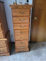 Front view of oak veneer 7-drawer tallboy chest showing brass hardware