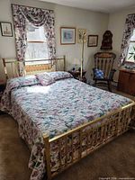 Full view of brass queen bed with mattress, comforter, pillows, curtains, coat rack visible