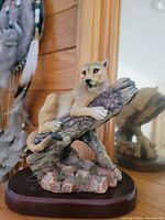 Mountain lion resin figurine reclining on log, front view