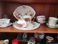 Full set on shelf: teapot, sugar bowl, creamer, oval platter, stacked cups and saucers