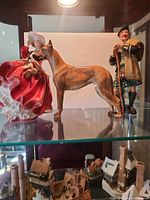 All three figurines on glass shelf: woman, dog, Scottish man