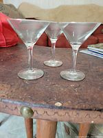 Three of the clear martini glasses angled on tabletop showing bowl and stem design