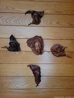 Overview of all five leather masks mounted on wood wall