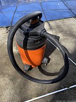 Front view of orange Shop-Vac with hose attached