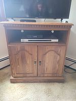 Front view of oak veneer TV stand with open shelf and closed cabinet doors