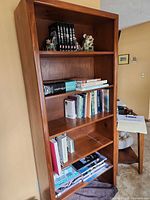 Full front view of bookcase showing five shelves and brown wood finish