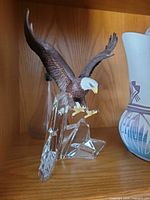 Front view of painted resin bald eagle figurine on clear faceted base