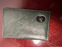 Front exterior of green leather wallet with metal logo
