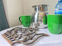 Group shot of carafe, trivet, two mugs