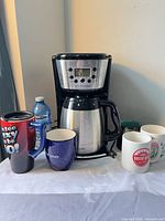 Front view showing coffee maker, carafe and six mugs