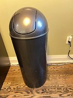 Full view of black plastic trash can with gray swing dome lid