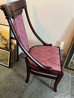 Side view of cherry wood chair showing curved arms and rose damask upholstery