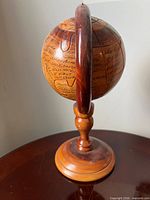 Front view of carved wooden globe in stand