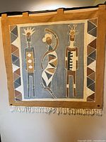 Full view of wall hanging showing figures, border, fringe and hanging loops