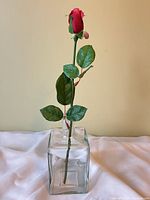 Front view of glass vase holding artificial rose