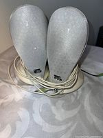 Front view of both JBL speakers, showing grills and audio cable