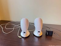 Front view of both white JBL speakers with attached cable and power adapter