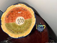 Top view of serving bowl showing inscription, olive branch motif, colour bands and scalloped edge
