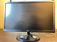 Front view of LG monitor on stand with power adapter and DVI cable