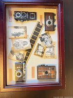 Top view showing glass lid with miniature cameras, film strip and vintage photos