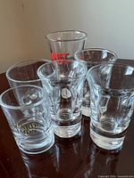 All six shot glasses grouped together showing logos and heavy bases