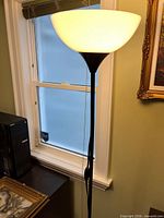 Lamp illuminated in room showing shade, pole and partial base