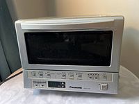 Front view of Panasonic NB-G110P toaster oven showing glass door and control panel
