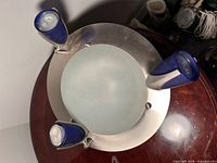 Top view showing brushed metal ring, frosted glass center, three blue spotlights