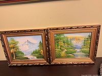 Front view of both framed landscape paintings side by side