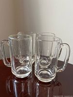 Front view of all four clear glass beer mugs on tabletop
