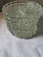 Stack of eight clear pressed-glass ashtrays showing textured sides