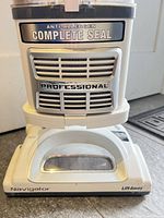 Dust cup and base showing Anti-Allergen Complete Seal Professional and Navigator Lift-Away branding