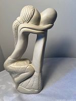 Front view of off-white stone sculpture depicting embracing couple