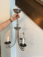 Hand holding chandelier showing full fixture, three arms, chain and canopy